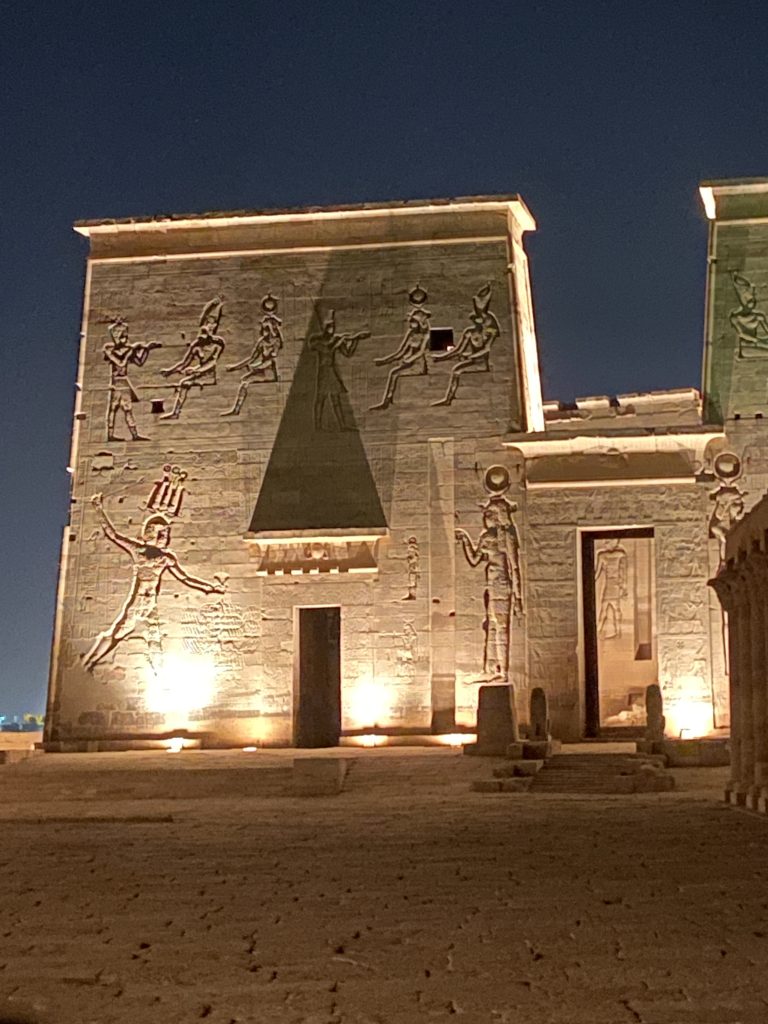 Ancient Egyptian reliefs on the illuminated walls of Philae Temple at night near Aswan, Egypt