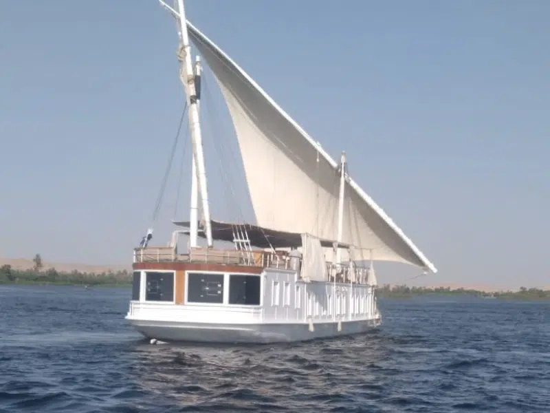 Traditional dahabiya sailboat Princess Kelly cruising on the Nile near Aswan with white sails and panoramic windows