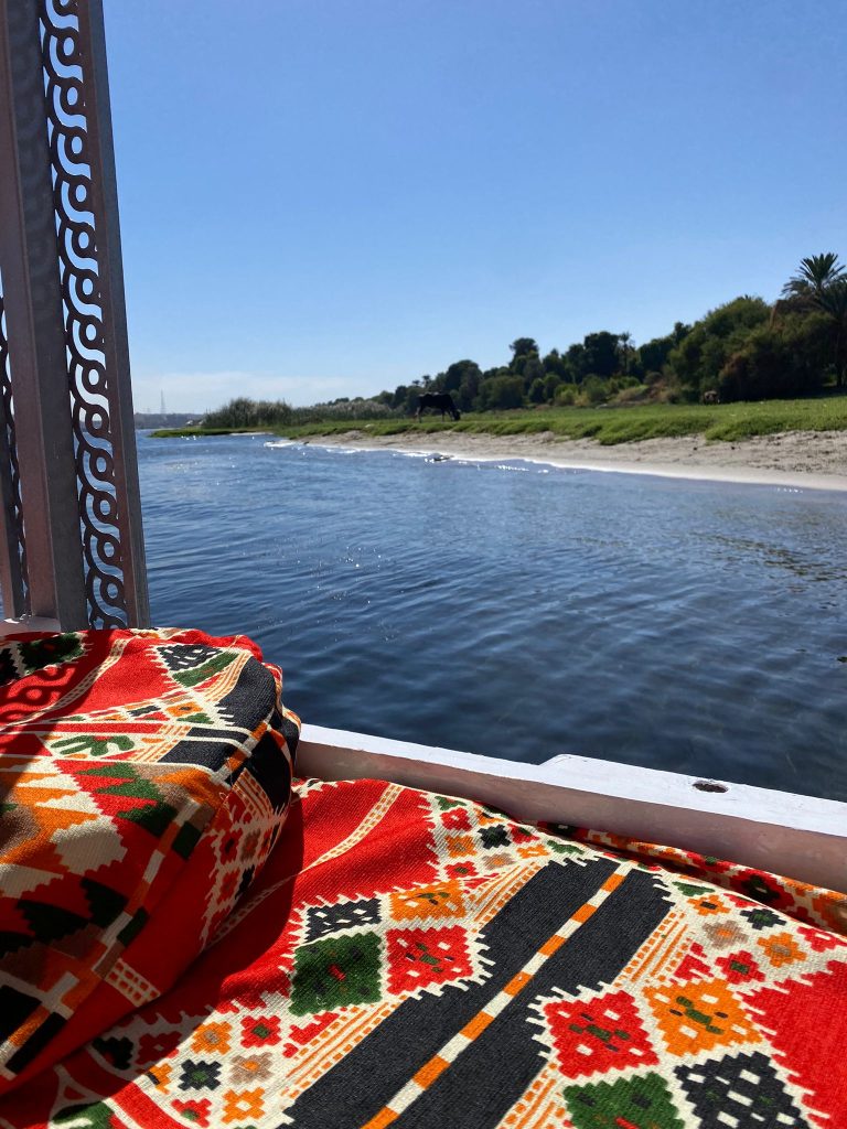Colorful cushions on the deck of the felucca Maitea overlooking the Nile riverbank near Aswan Egypt