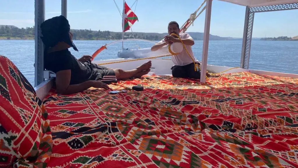 Felucca crew handling ropes and sail on a traditional Nile sailing boat in Upper Egypt
